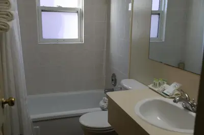 a bathroom with a sink and a toilet and a mirror at SlumberLodge Hotel in Penticton