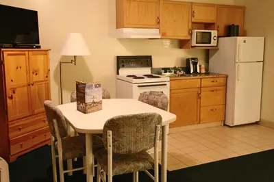 a kitchen with a table and a white refrigerator at SlumberLodge Hotel in Penticton