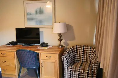 a room with a desk with a tv and a chair at SlumberLodge Hotel in Penticton