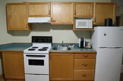a kitchen with a white refrigerator and a sink at SlumberLodge Hotel in Penticton