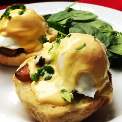 two muffins with cheese and greens on a white plate at Alert Bay Lodge in Alert Bay