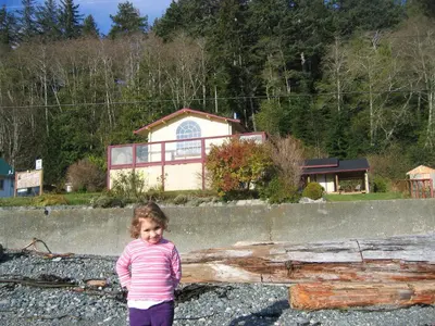 a little girl standing in front of a log at Alert Bay Lodge in Alert Bay