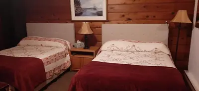 a room with two beds and a table with lamps at Alert Bay Lodge in Alert Bay