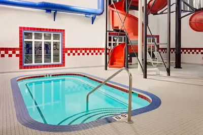 a swimming pool with a slide in a building at Ramada by Wyndham Stettler in Stettler