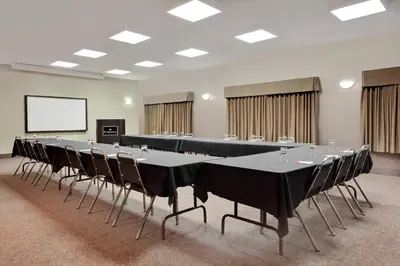 a conference room with tables and chairs and a screen at Ramada by Wyndham Stettler in Stettler
