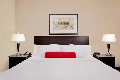 a bedroom with a large white bed with a red pillow at Ramada by Wyndham Stettler in Stettler
