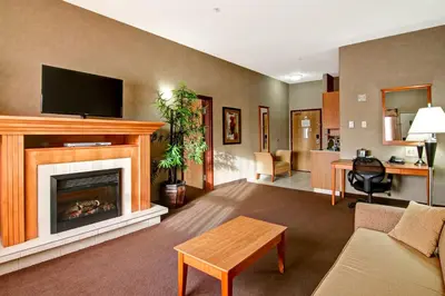 a living room with a fireplace and a tv at Canalta Stettler in Stettler