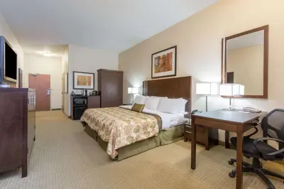 a hotel room with a bed and a desk and a mirror at Ramada by Wyndham Wainwright in Wainwright