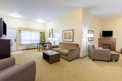 a living room with a couch and chairs and a television at Ramada by Wyndham Wainwright in Wainwright