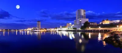 a city skyline at night with the moon over the water at Diplomat Motel in Nanaimo