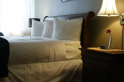 a bedroom with a bed with a lamp on a night stand at R&R Inn & Suites in Camrose