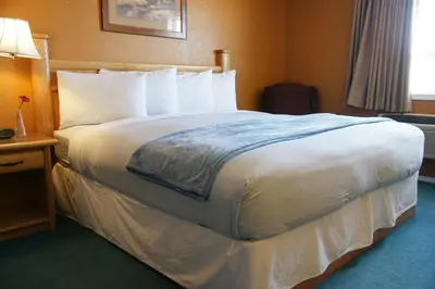 a hotel room with a large bed with white sheets at R&R Inn & Suites in Camrose