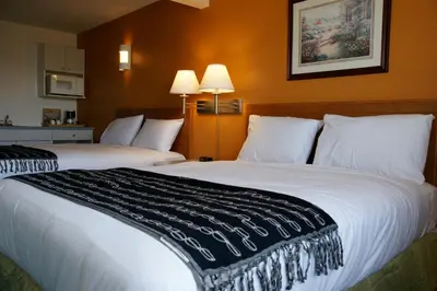 two beds in a hotel room with white pillows at R&R Inn & Suites in Camrose