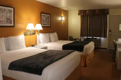 a hotel room with two beds and a table at R&R Inn & Suites in Camrose