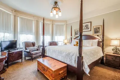 a bedroom with a large bed and a television at O Canada House Bed & Breakfast in Vancouver