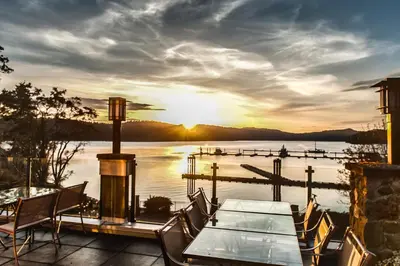 a table and chairs on a patio with a view of a lake at Poets Cove Resort & Spa in Bedwell Harbour