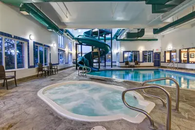 a jacuzzi tub in a pool with a slide at Canalta Rocky Mountain House in Rocky Mountain House
