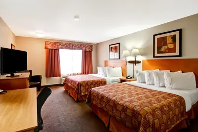 a hotel room with two beds and a flat screen tv at Canalta Rocky Mountain House in Rocky Mountain House