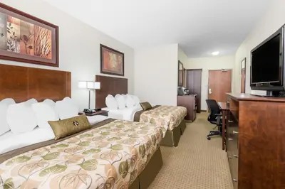 a hotel room with two beds and a flat screen tv at Ramada by Wyndham Olds in Olds