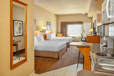 a hotel room with two beds and a kitchen at Clarion Pointe in Rimbey