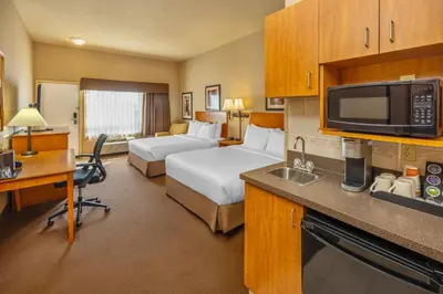 a hotel room with two beds and a desk and a kitchen at Clarion Pointe in Rimbey