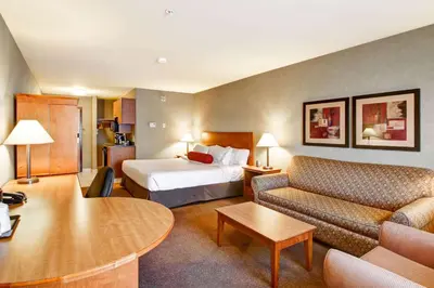 a hotel room with a bed and a couch at Ramada by Wyndham Ponoka in Ponoka