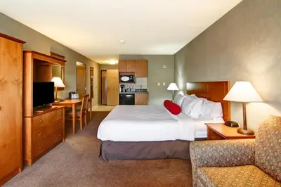a hotel room with a large bed and a couch at Ramada by Wyndham Ponoka in Ponoka
