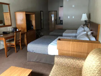 a hotel room with two beds and a desk at Ramada by Wyndham Ponoka in Ponoka