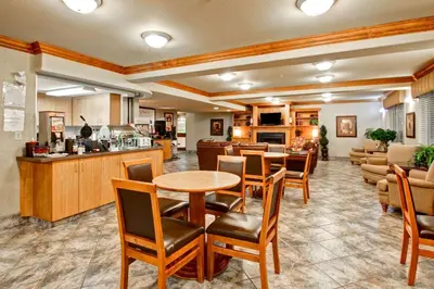 a lobby with tables and chairs and a kitchen at Ramada by Wyndham Ponoka in Ponoka