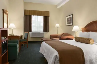 a hotel room with a bed and chairs and a television at Travelodge by Wyndham Strathmore in Strathmore