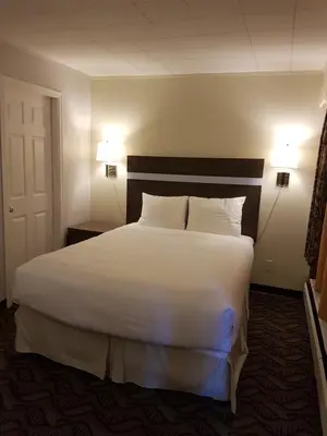 a bedroom with a large bed with white sheets and pillows at Holiday Motel & RV Resort in Hope