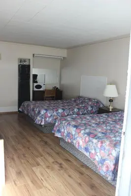 a bedroom with a bed and a table with a lamp at Raval Paradise Motel and RV Park in Youngstown