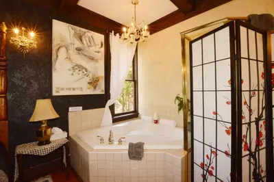 a bathroom with a tub and a window and a chandelier at Marketa's Bed and Breakfast in Victoria
