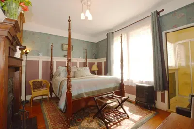 a bedroom with a canopy bed and a fireplace at Marketa's Bed and Breakfast in Victoria