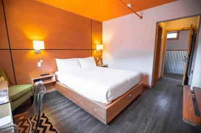 a bedroom with a large white bed and a chair at Adventure Hotel in Nelson