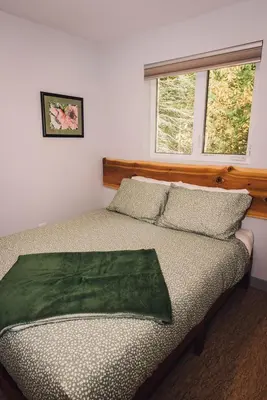 a bedroom with a bed with a green blanket on it at Across the Creek Cabins in Clearwater