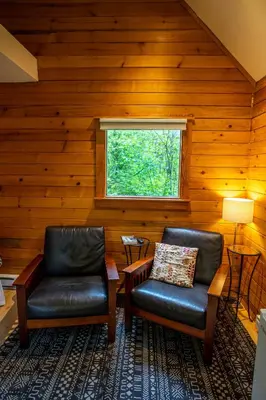 two leather chairs in a room with a window at Across the Creek Cabins in Clearwater