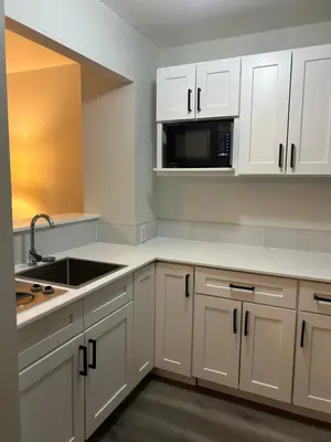 a kitchen with white cabinets and a sink and a microwave at Rimbey Motor Inn in Rimbey