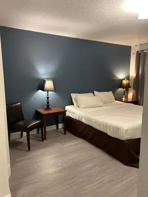 a bedroom with a bed and a chair and a blue wall at Rimbey Motor Inn in Rimbey