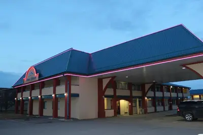 a building with a car parked in a parking lot at Deer Park Inn in Red Deer