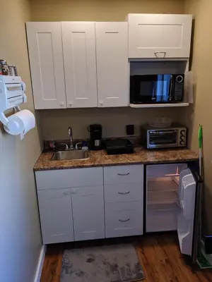 a kitchen with white cabinets and a sink and a microwave at Nimpkish Hotel in Alert Bay