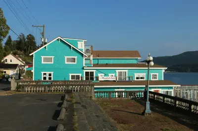 a blue house with a fence in front of it at Nimpkish Hotel in Alert Bay