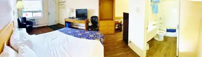 a bedroom with a bed and a desk with a television at Grande Mountain Lodge in Grande Cache