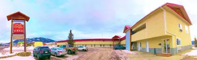 a large building with cars parked in front of it at Grande Mountain Lodge in Grande Cache