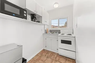 a white kitchen with a stove and a microwave at 5000 Motel in Penticton