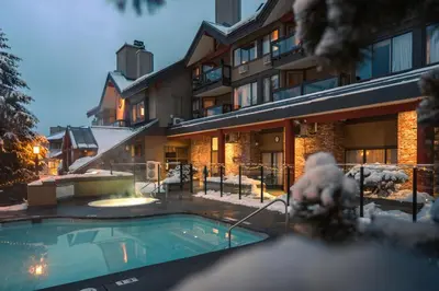 a building with a swimming pool in the snow at Whistler Village Inn & Suites in Whistler