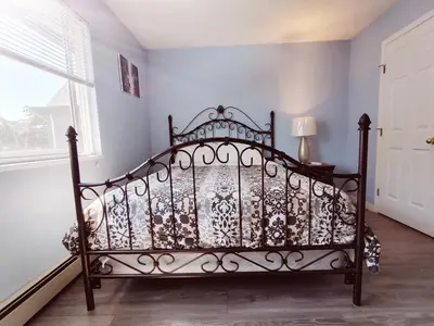 an iron bed in a room with a window at Bed Plus YVR in Richmond