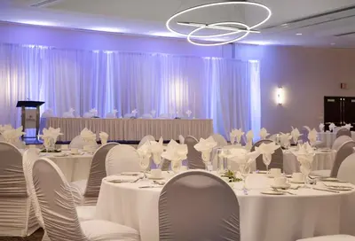 a banquet room with white tables and chairs and a chandelier at Hilton Vancouver Metrotown in Burnaby