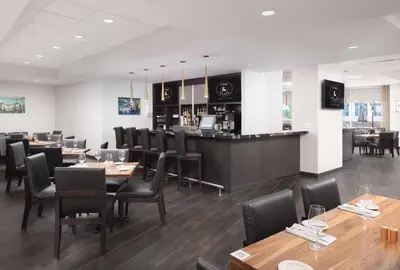 a restaurant with tables and chairs and a bar at Hilton Vancouver Metrotown in Burnaby