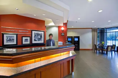 a man standing at a reception counter in a hotel lobby at Hampton Inn - Vancouver Airport/Richmond in Richmond